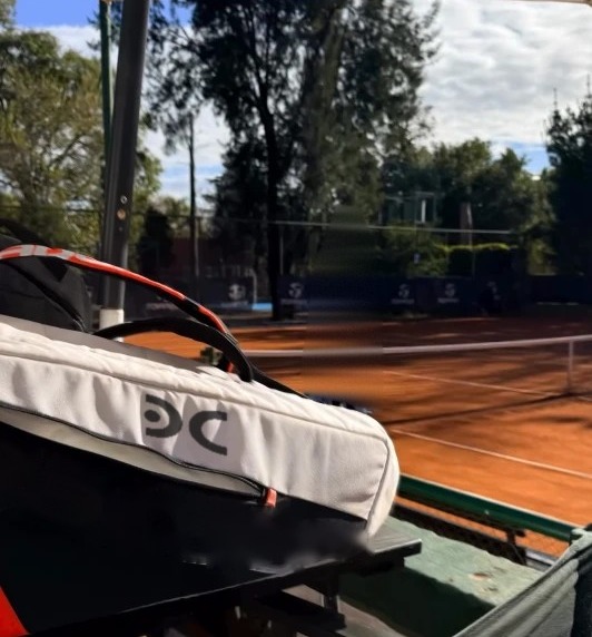 Cancha de tierra batida vista desde el banco, con el bolso deportivo del Dr. De Caso